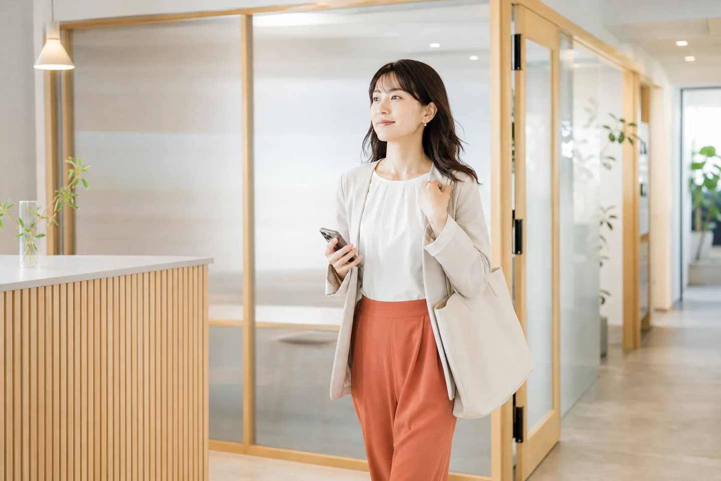 整ったワークスペースでスマートフォンを確認する女性