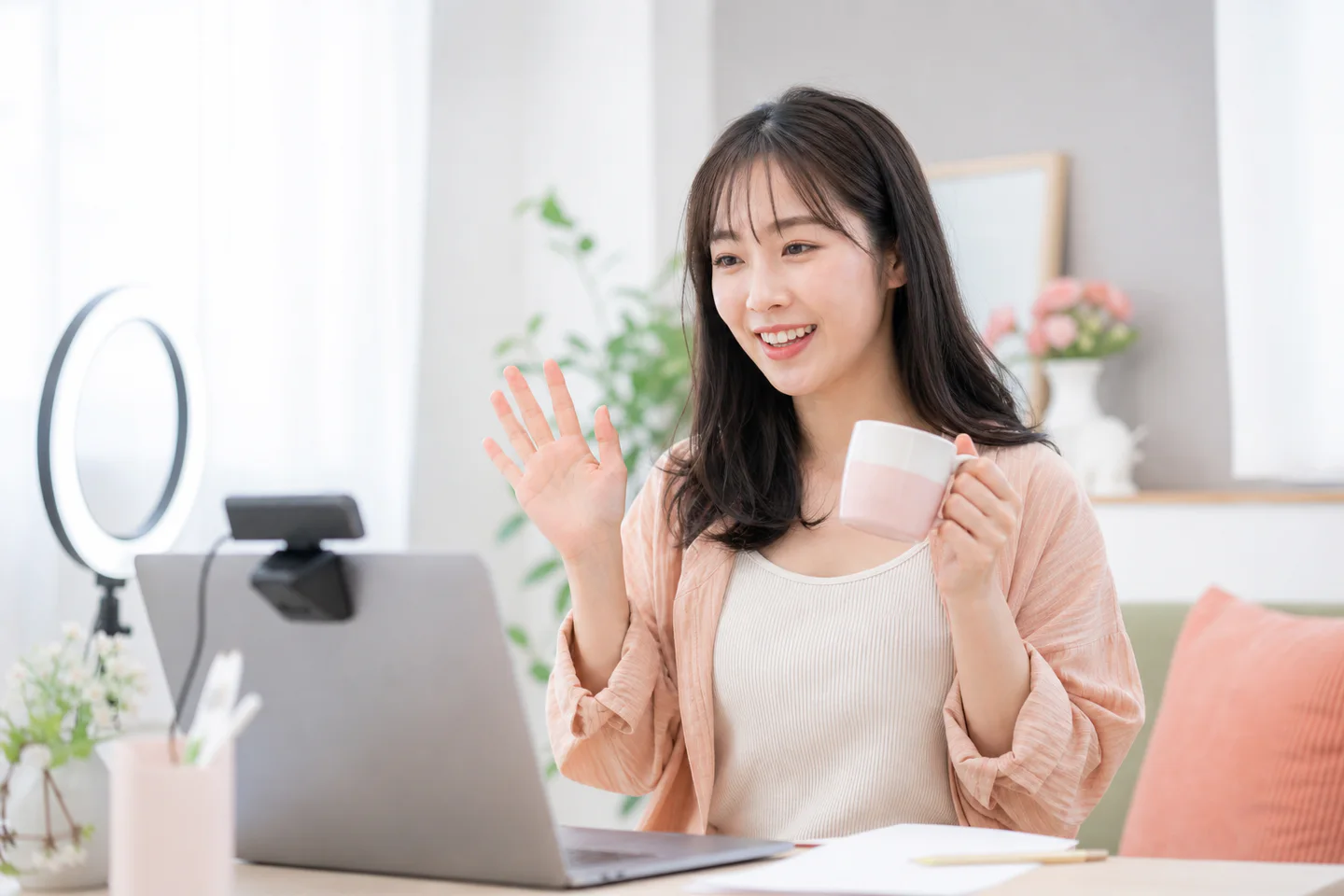 明るい自宅のデスクで会話中心の仕事を準備する女性の編集イメージ